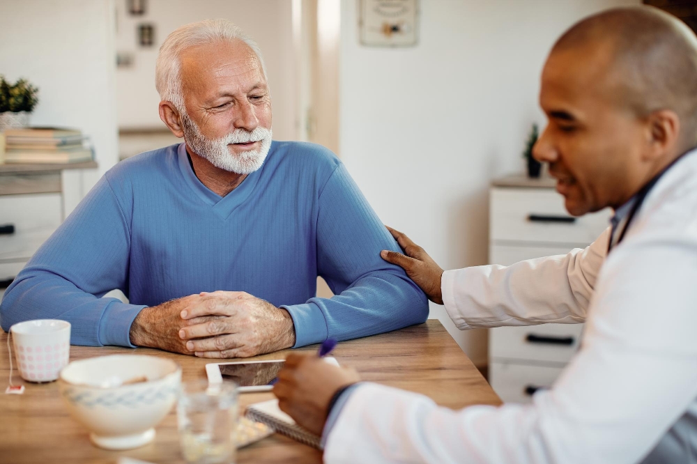 A mature man talking with his doctor during a home visit about his health.